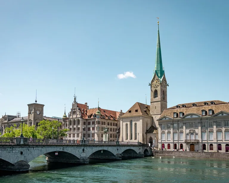 Fraumünster exterior with green steeple beside Limmat; other skyline buildings are not venue pins.