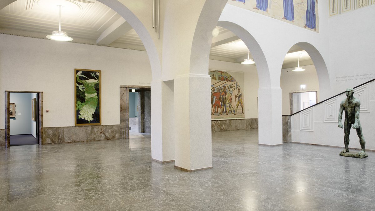 Moser Foyer 3 with white arches, murals, sculpture and stairs; not a claim that the moving concert occupies only this foyer.